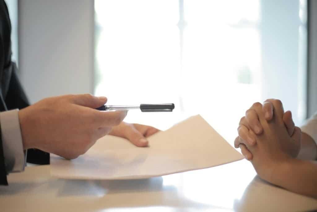 A man in a suit is holding a pen and talking to a woman.