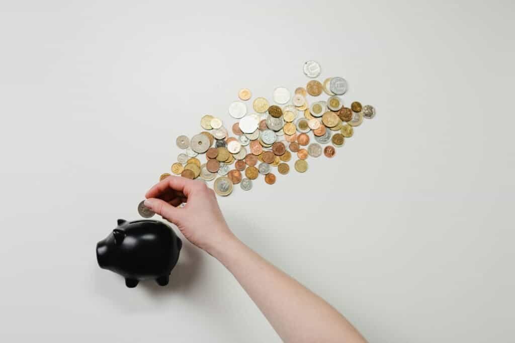 A hand putting a coin into a piggy bank.