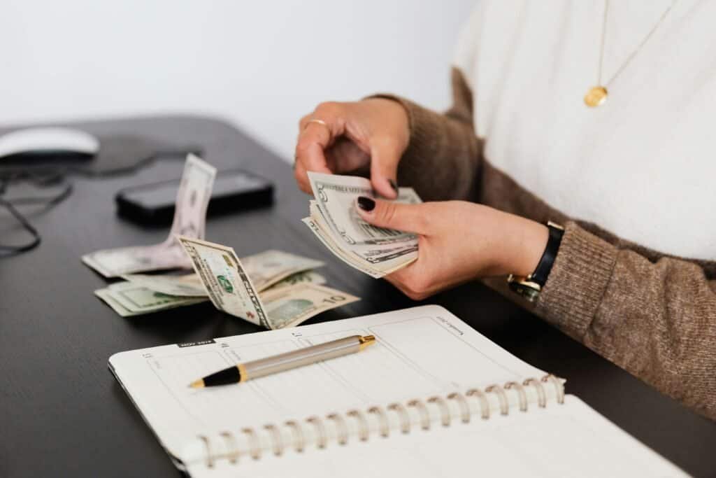 A woman is putting money into a notebook at a desk.