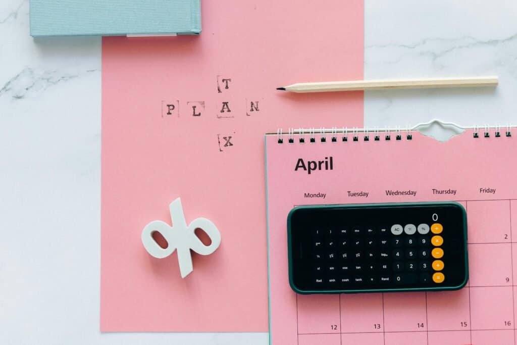 A pink calendar with a calculator and pencil on it.